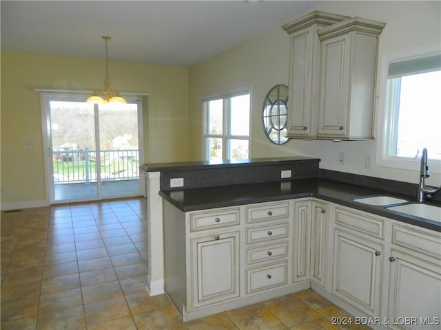 kitchen with dark countertops, a sink, a peninsula, and light tile patterned floors