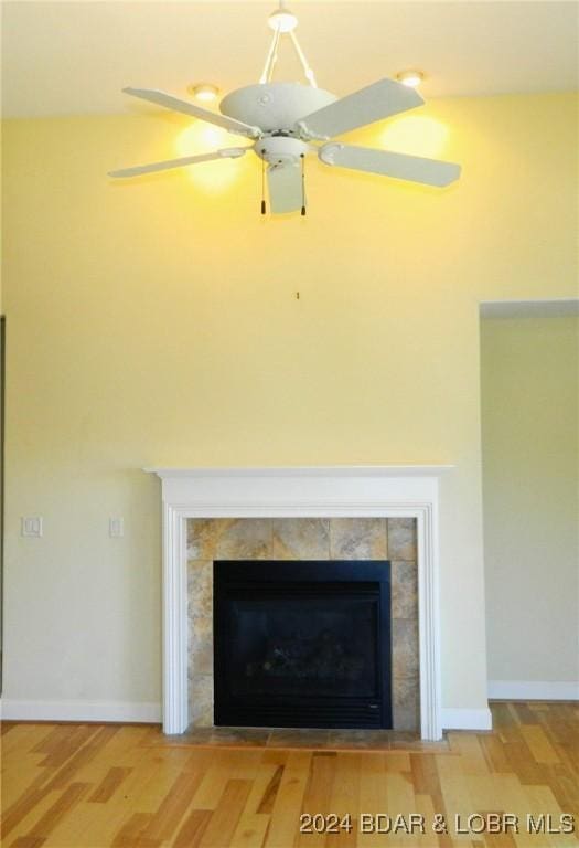 room details featuring ceiling fan, wood finished floors, a tile fireplace, and baseboards