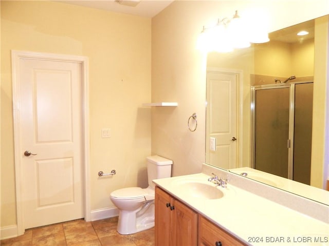 bathroom with toilet, a stall shower, vanity, baseboards, and tile patterned floors