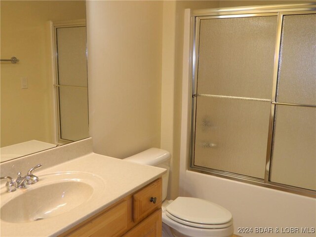 full bathroom featuring combined bath / shower with glass door, vanity, and toilet