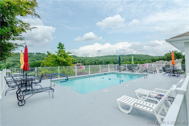 community pool with a patio area and fence