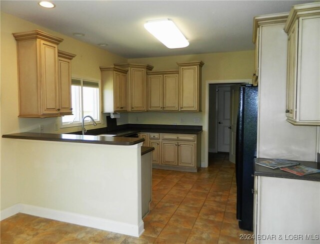 kitchen with sink, black fridge, tile patterned floors, and light brown cabinets