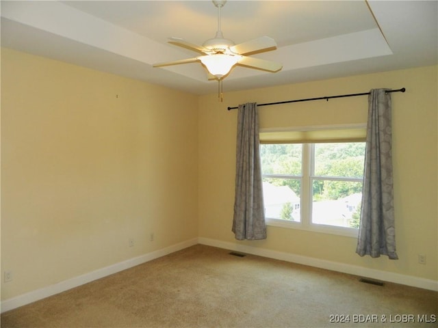 empty room featuring light colored carpet, visible vents, ceiling fan, and baseboards