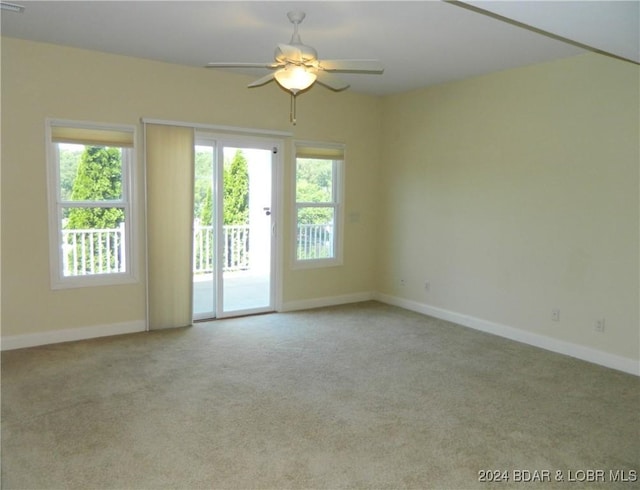 empty room with light carpet, a ceiling fan, and baseboards