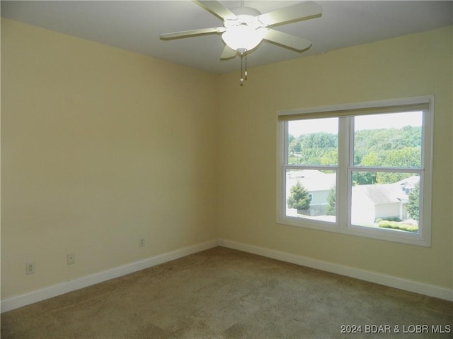 empty room featuring light carpet, ceiling fan, and baseboards