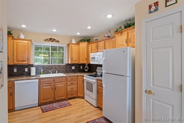 kitchen featuring backsplash, sink, white appliances, and light hardwood / wood-style floors