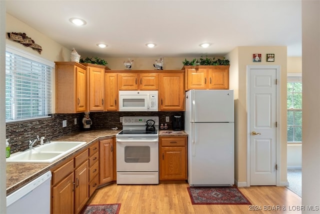 kitchen featuring white appliances, backsplash, sink, and light hardwood / wood-style floors