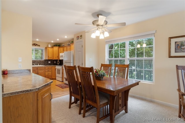 dining space featuring light colored carpet, a wealth of natural light, sink, and ceiling fan