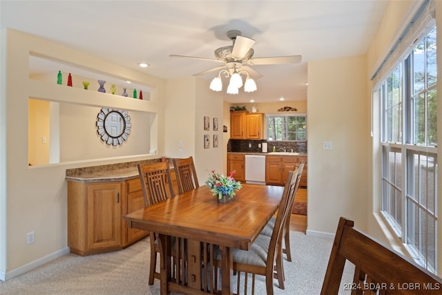 carpeted dining room featuring a wealth of natural light, sink, and ceiling fan