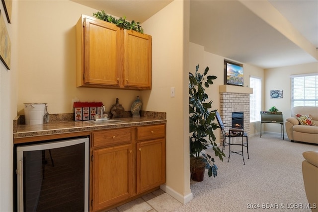 bar featuring light carpet, sink, wine cooler, and a brick fireplace