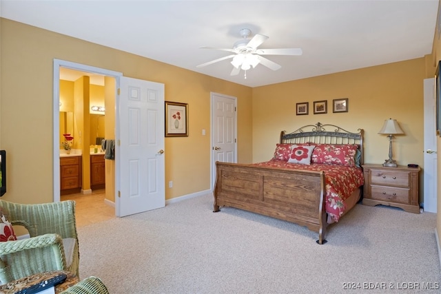 bedroom with light colored carpet, ceiling fan, and ensuite bath