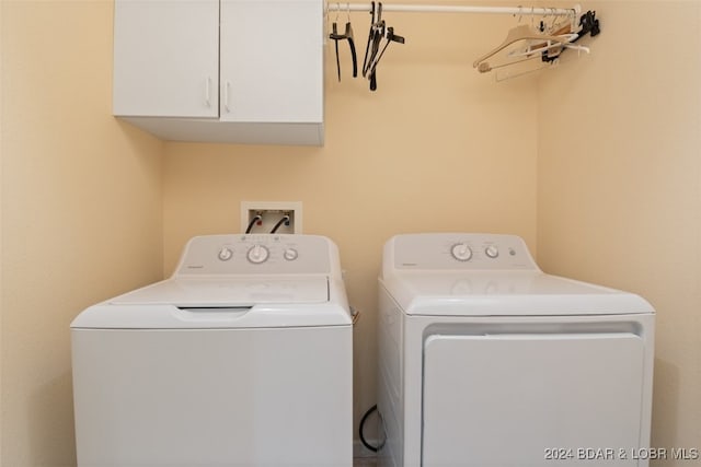 clothes washing area featuring washer and clothes dryer and cabinets