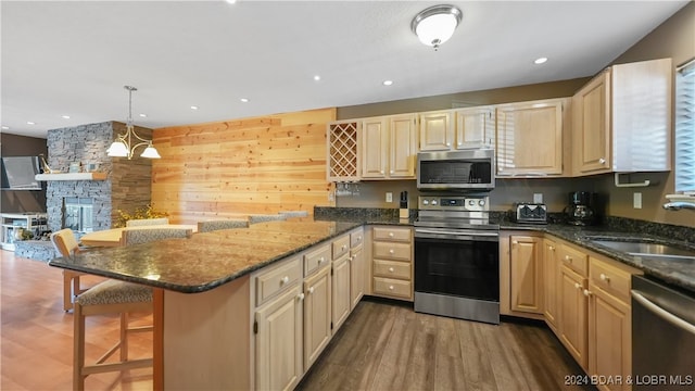 kitchen featuring hardwood / wood-style floors, a kitchen bar, a fireplace, stainless steel appliances, and kitchen peninsula