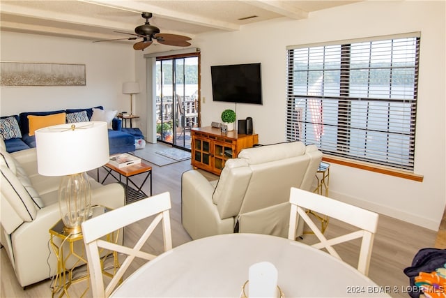 living room with ceiling fan, light hardwood / wood-style floors, and beamed ceiling