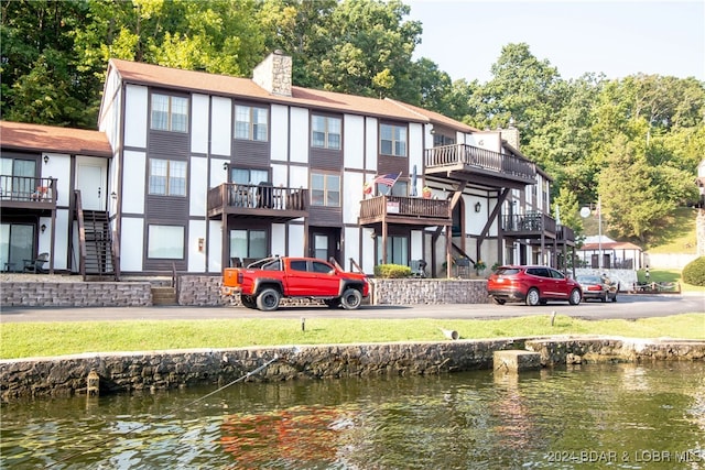 dock area with a balcony, a yard, and a water view