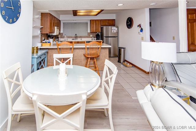 dining room with a textured ceiling, light hardwood / wood-style flooring, and sink