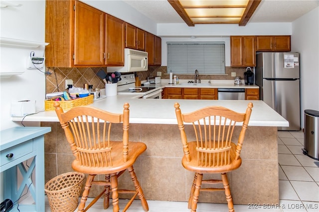 kitchen featuring stainless steel appliances, sink, backsplash, and kitchen peninsula