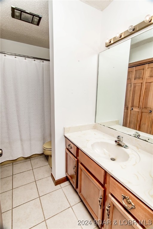 bathroom with a textured ceiling, vanity, curtained shower, tile patterned flooring, and toilet