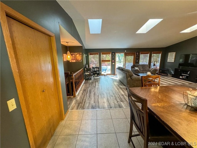 dining area with light tile patterned floors, lofted ceiling with skylight, and an inviting chandelier