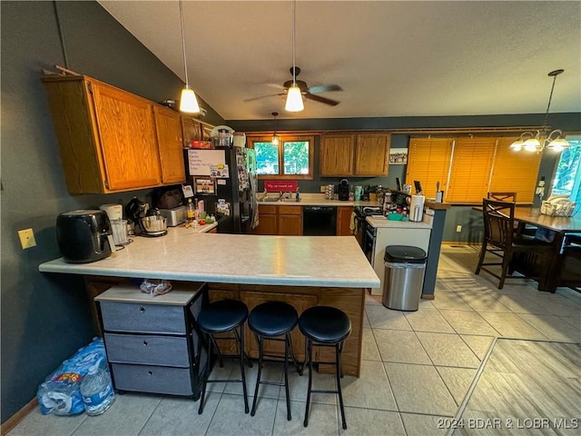 kitchen featuring kitchen peninsula, a kitchen breakfast bar, pendant lighting, ceiling fan with notable chandelier, and black appliances