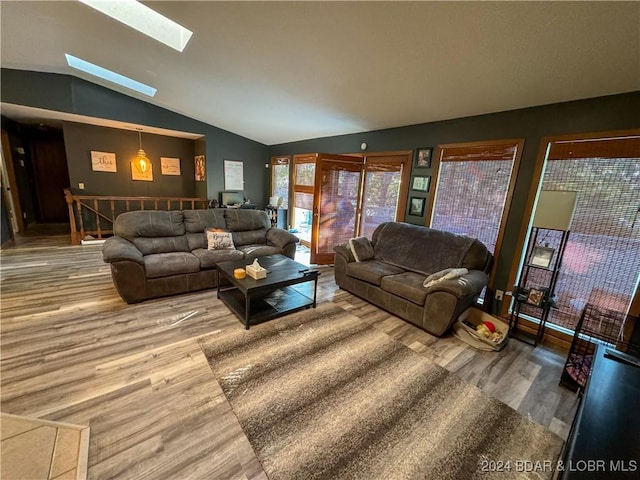 living room featuring vaulted ceiling with skylight and wood-type flooring