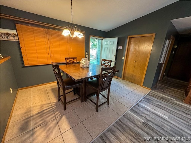 tiled dining room with vaulted ceiling and a notable chandelier