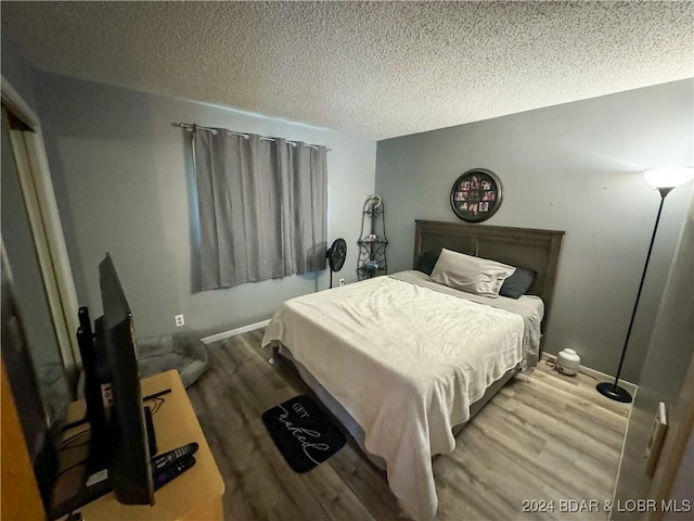 bedroom featuring a textured ceiling and light hardwood / wood-style flooring