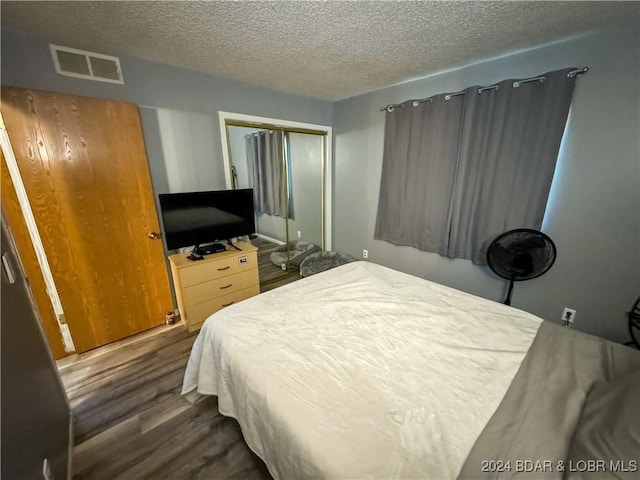 bedroom featuring a textured ceiling, a closet, and dark hardwood / wood-style flooring