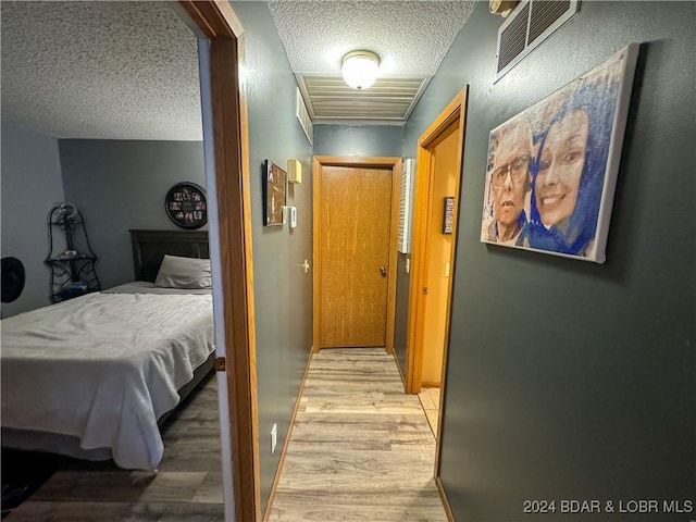 corridor featuring light wood-type flooring and a textured ceiling