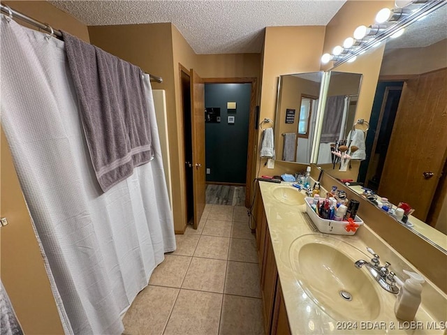 bathroom with a textured ceiling, vanity, and tile patterned flooring