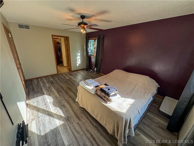 bedroom with ceiling fan, a textured ceiling, and dark hardwood / wood-style flooring