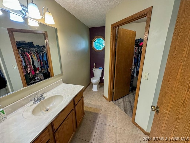 bathroom with toilet, vanity, tile patterned flooring, an inviting chandelier, and a textured ceiling