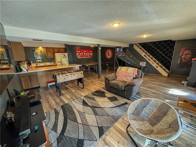 playroom featuring a textured ceiling and light hardwood / wood-style flooring