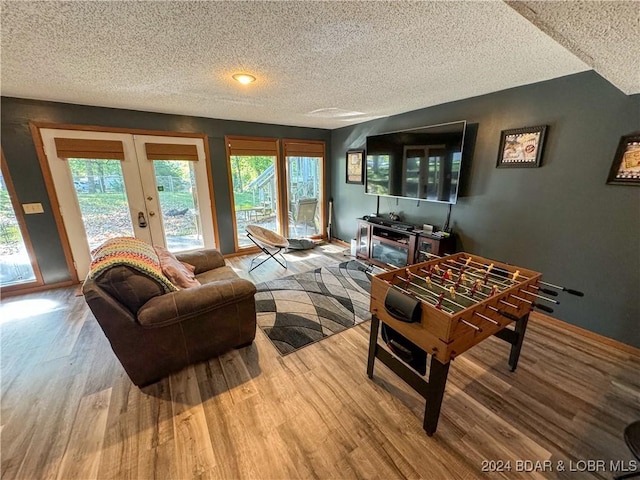 living room featuring light hardwood / wood-style floors, a textured ceiling, and french doors