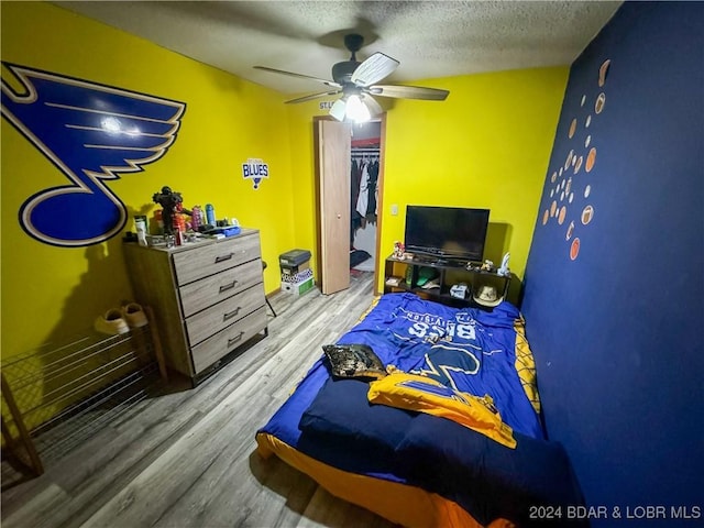 bedroom with ceiling fan, a textured ceiling, hardwood / wood-style flooring, and a closet