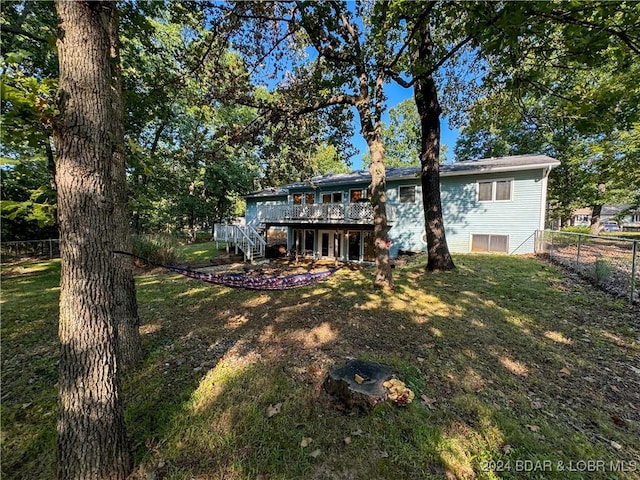 rear view of house featuring a lawn and a wooden deck