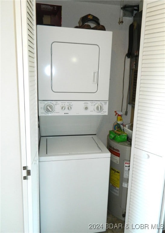 washroom featuring stacked washer / dryer and water heater