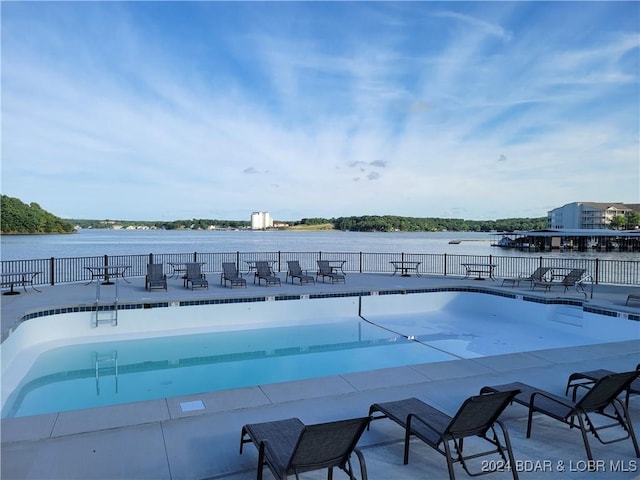 view of swimming pool with a patio area, a water view, and fence