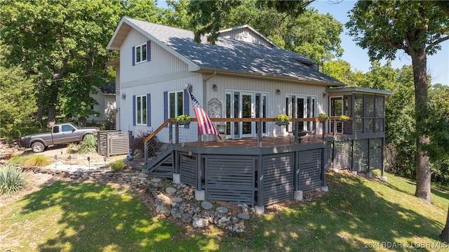 back of property with a sunroom, a yard, a wooden deck, and french doors