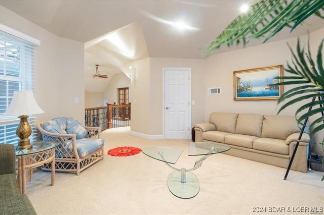 living room featuring ceiling fan, carpet flooring, and lofted ceiling