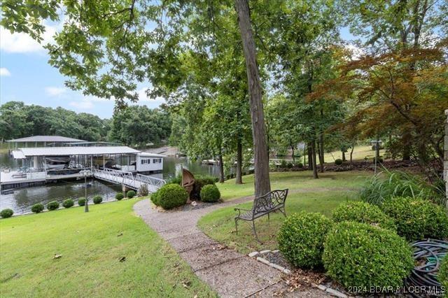 surrounding community featuring a dock, a lawn, and a water view