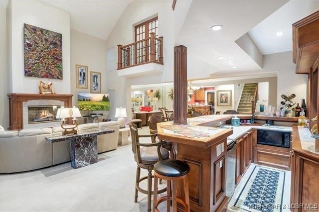 kitchen featuring high vaulted ceiling, black microwave, and light carpet