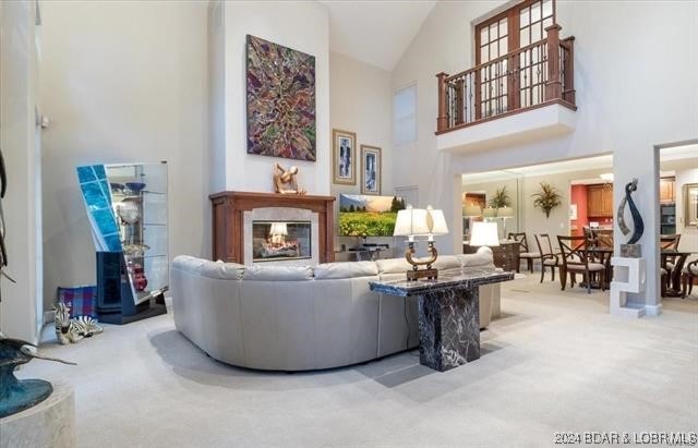 carpeted living room with a multi sided fireplace and high vaulted ceiling