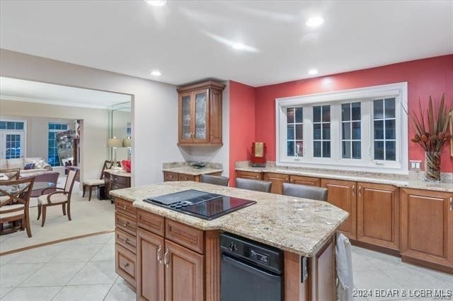 kitchen with a center island, light stone counters, black electric cooktop, and light tile patterned floors