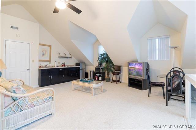 carpeted living room with ceiling fan and lofted ceiling