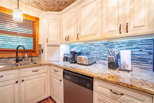 kitchen with light stone counters, stainless steel dishwasher, decorative backsplash, and a sink