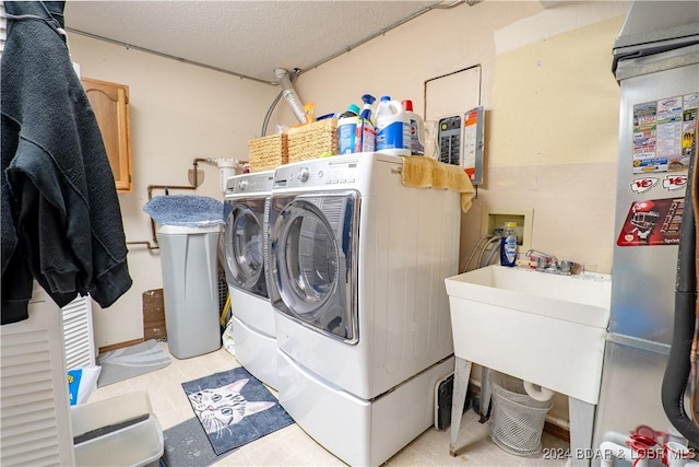 laundry area with washing machine and clothes dryer, a sink, laundry area, and a textured ceiling