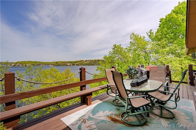 wooden terrace with a water view and outdoor dining area