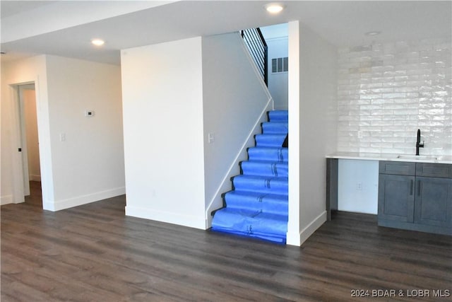 staircase with indoor wet bar and hardwood / wood-style floors