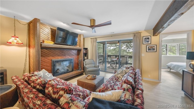 living room featuring ceiling fan, light hardwood / wood-style flooring, beamed ceiling, and a healthy amount of sunlight